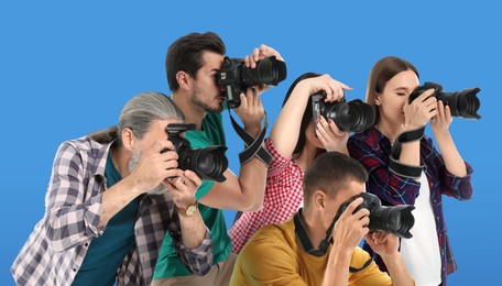 Image of Group of professional photographers with cameras on light blue background