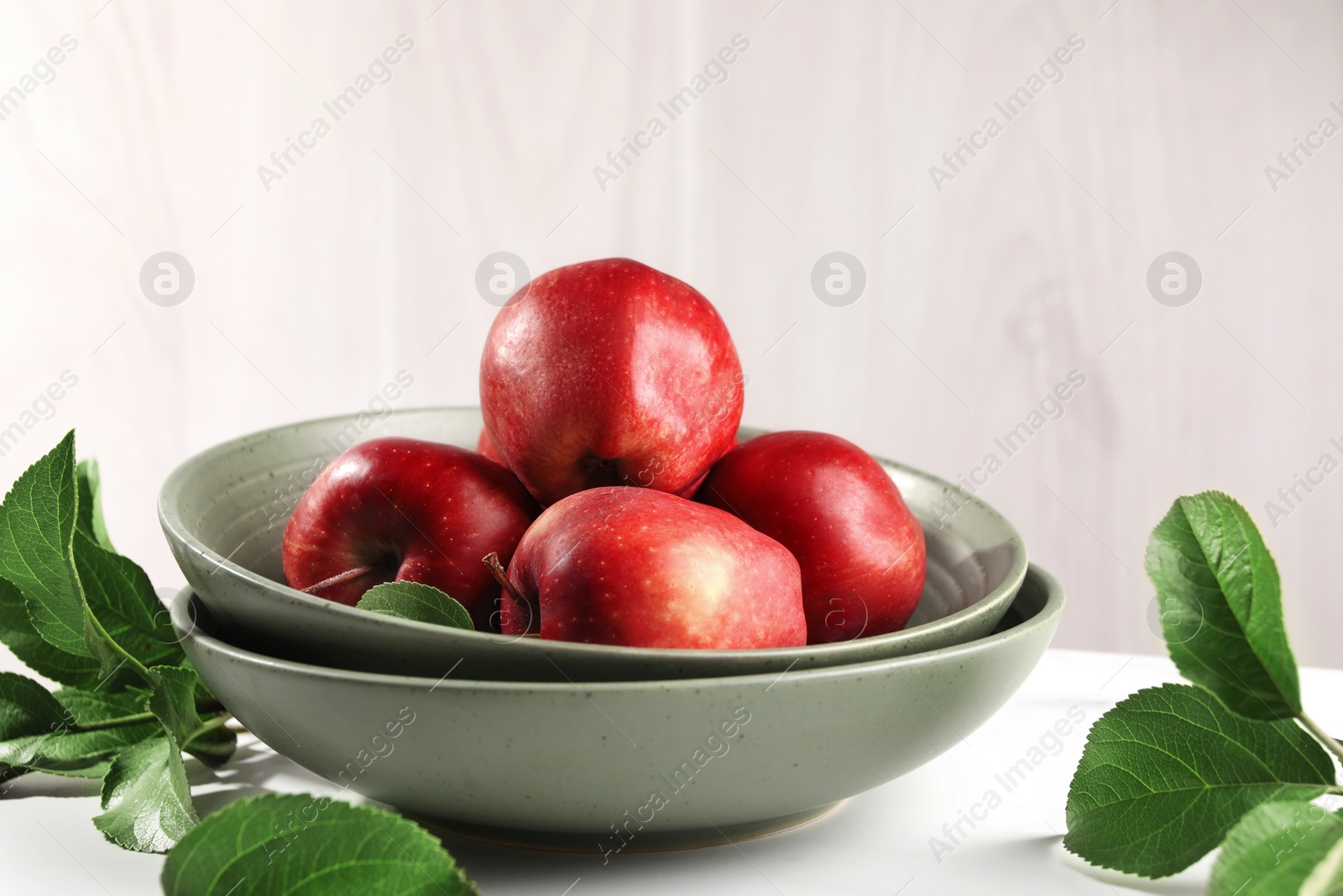 Photo of Fresh red apples and leaves on white table