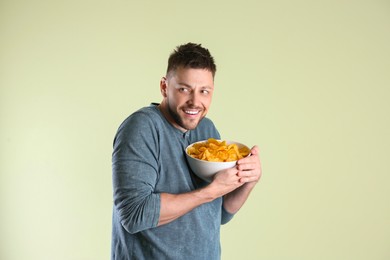 Greedy man hiding bowl with chips on light background