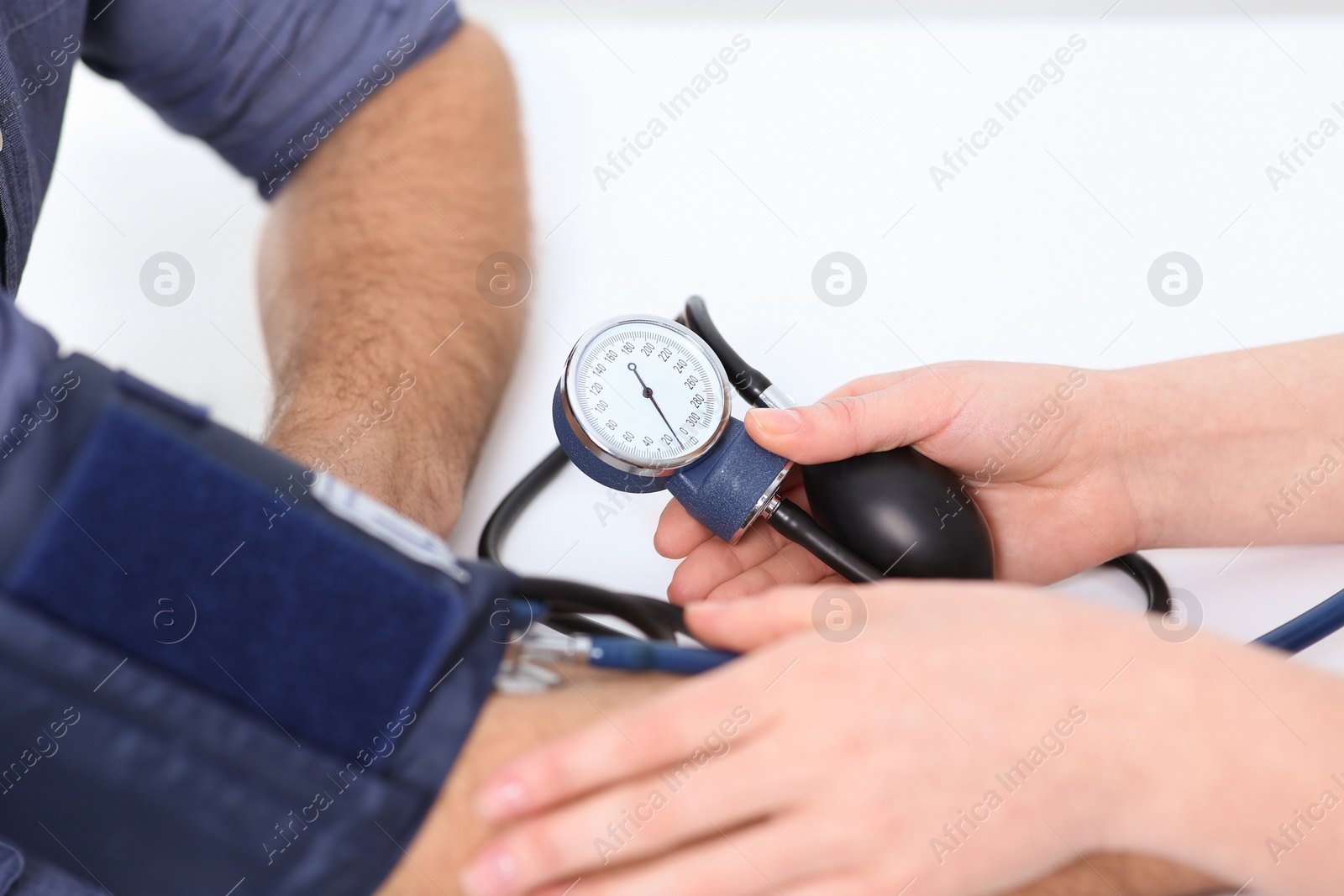 Photo of Doctor checking blood pressure of man in clinic, closeup