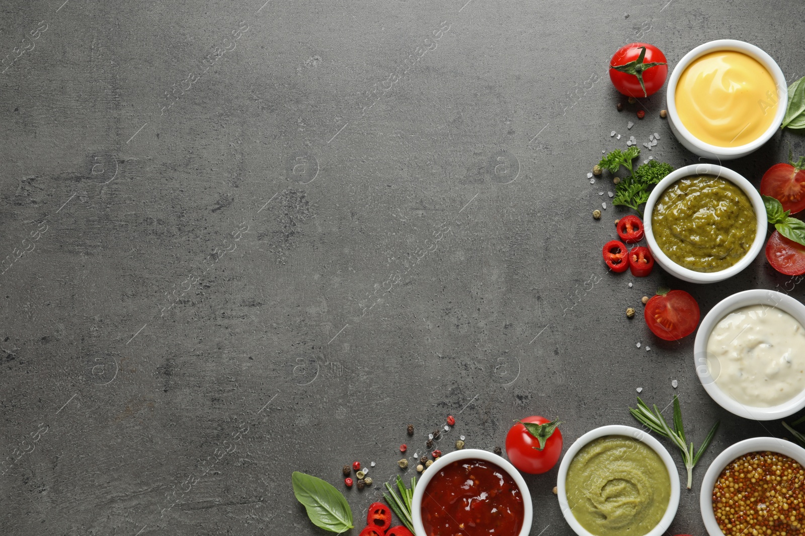 Photo of Bowls with different sauces and ingredients on gray background, flat lay. Space for text