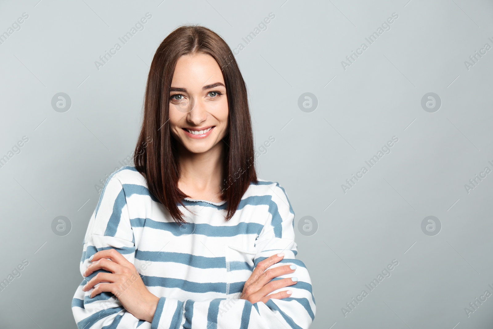 Photo of Portrait of pretty young woman with gorgeous chestnut hair and charming smile on light grey background, space for text