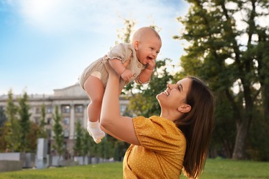 Happy mother with adorable baby walking in park on sunny day