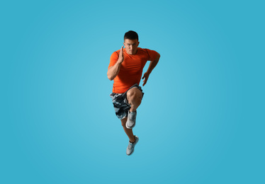 Photo of Athletic young man running on light blue background