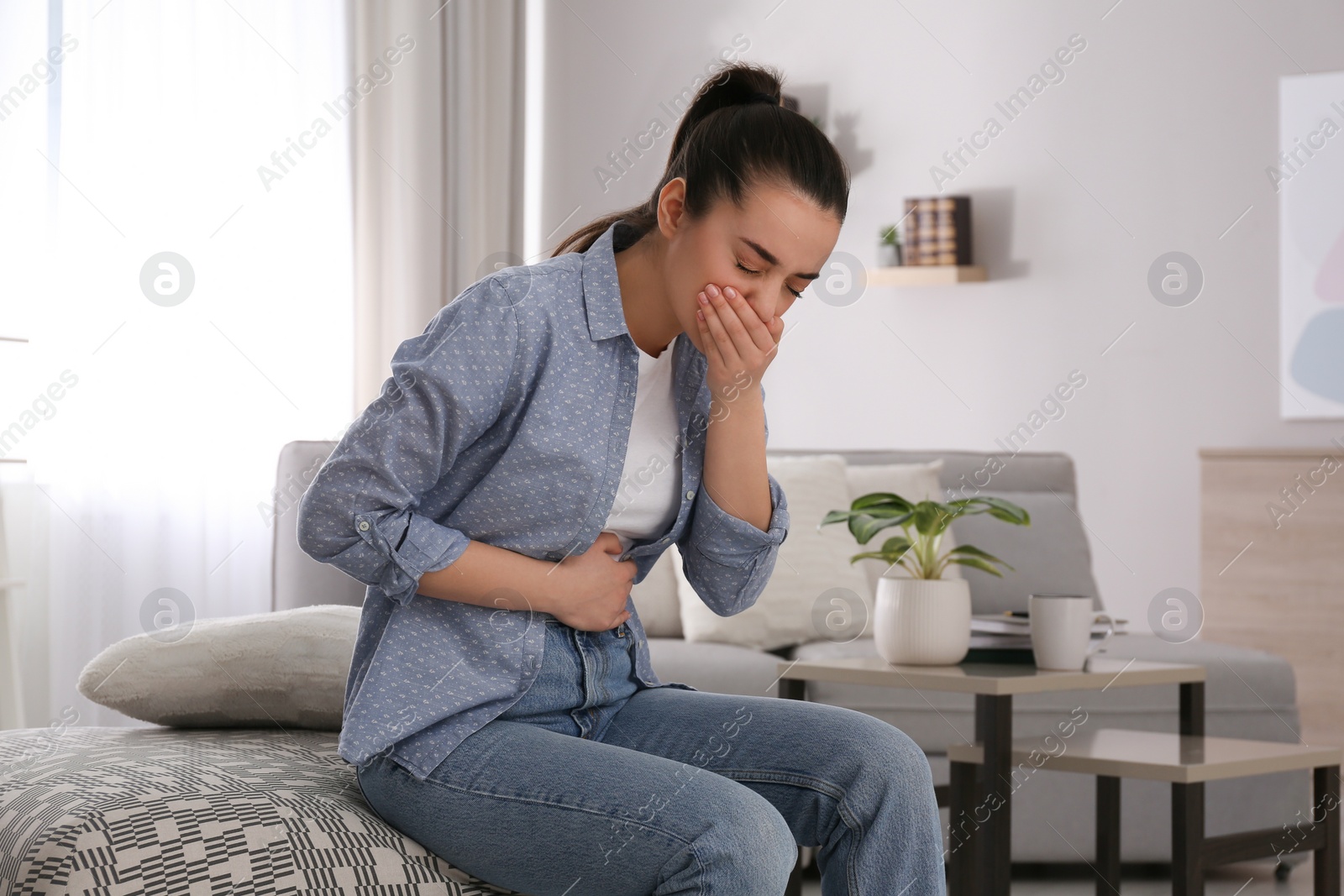 Photo of Young woman suffering from nausea at home. Food poisoning