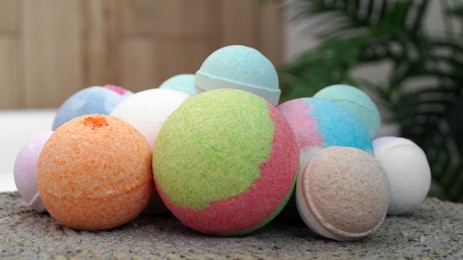Photo of Many different colorful bath bombs on wicker mat in bathroom, closeup