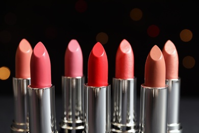 Photo of Different lipsticks against blurred lights. Cosmetic product