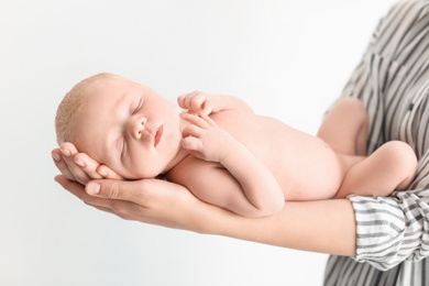 Photo of Young mother holding her newborn baby on light background