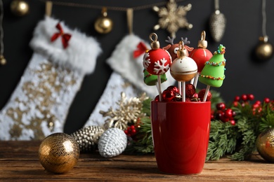 Photo of Delicious Christmas themed cake pops and festive decor on wooden table