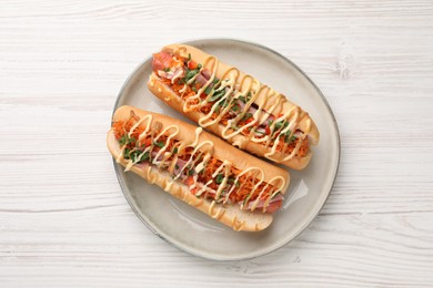 Photo of Delicious hot dogs with bacon, carrot and parsley on white wooden table, top view