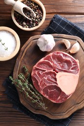 Flat lay composition of raw beef meat and spices on wooden table