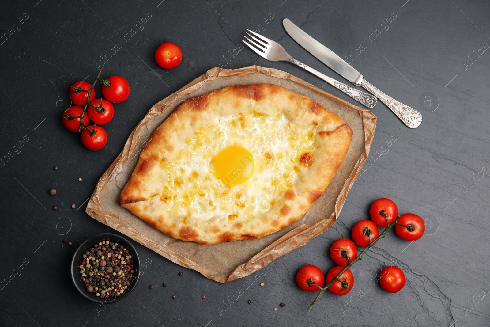 Photo of Fresh delicious Adjarian khachapuri served on black table, flat lay