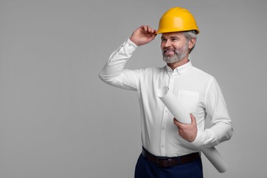 Photo of Architect in hard hat holding draft on grey background. Space for text