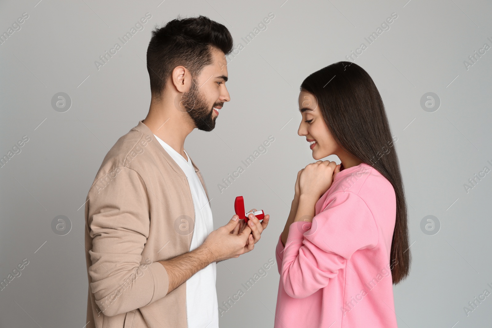 Photo of Man with engagement ring making marriage proposal to girlfriend on light grey background