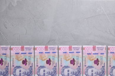Photo of Ukrainian money on grey background, flat lay. Space for text