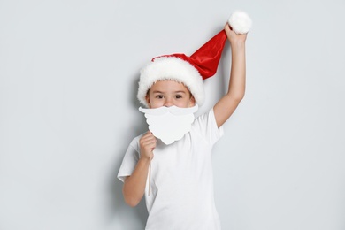 Cute little boy with Santa hat and white beard prop on white background. Christmas celebration