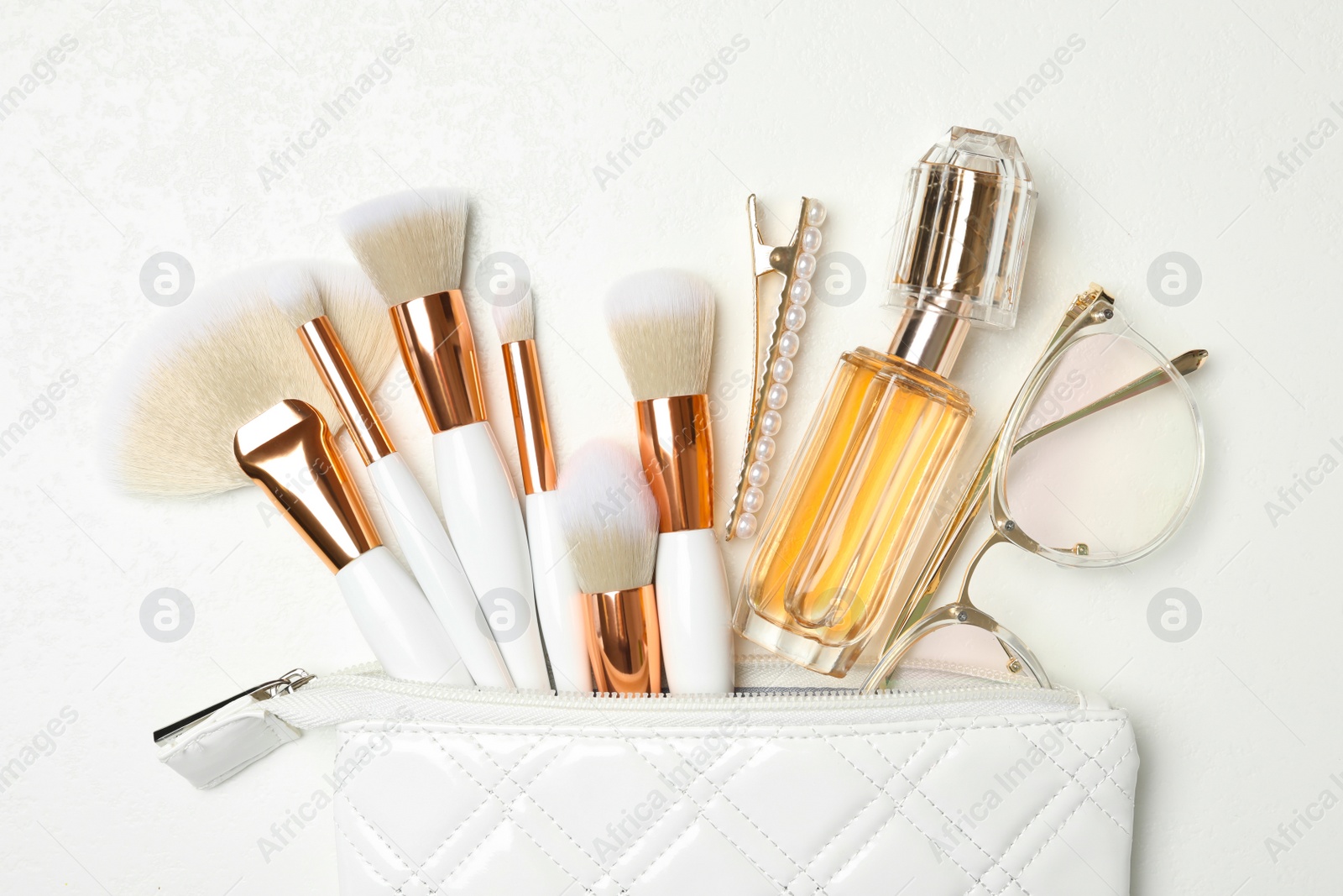 Photo of Cosmetic bag with makeup products and beauty accessories on white background, flat lay
