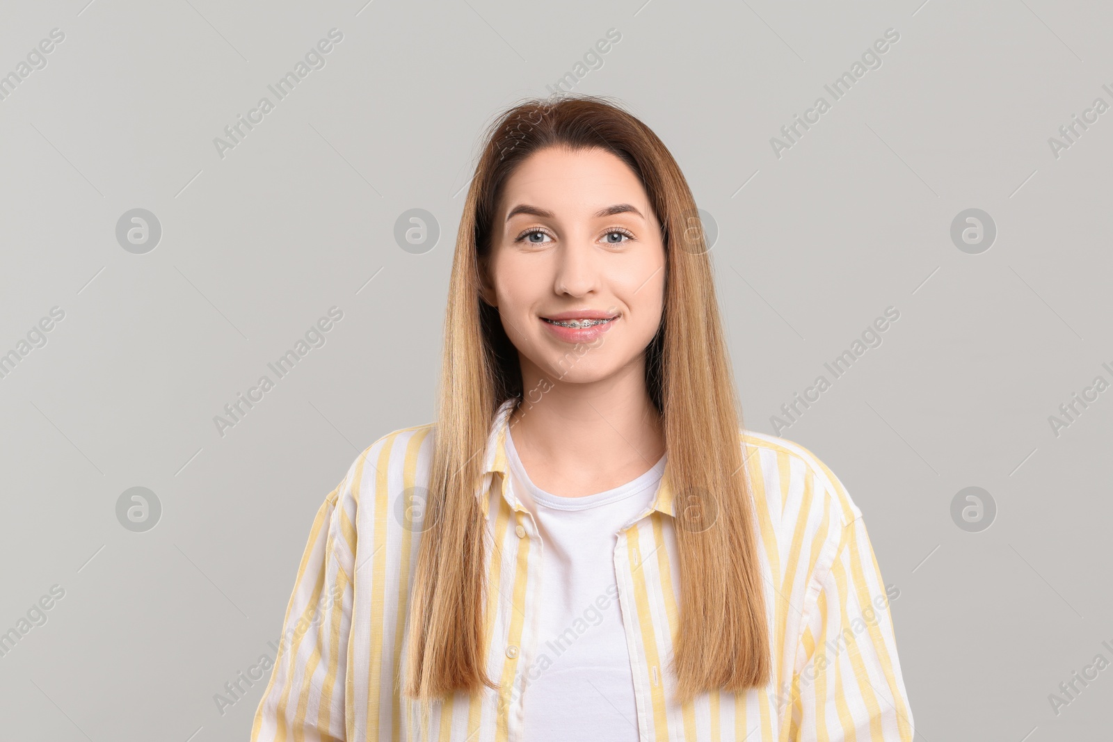 Photo of Portrait of smiling woman with dental braces on grey background