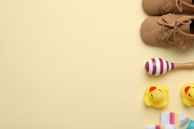 Photo of Flat lay composition with child's booties and toys on beige background, space for text