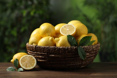 Photo of Fresh lemons in wicker basket on wooden table