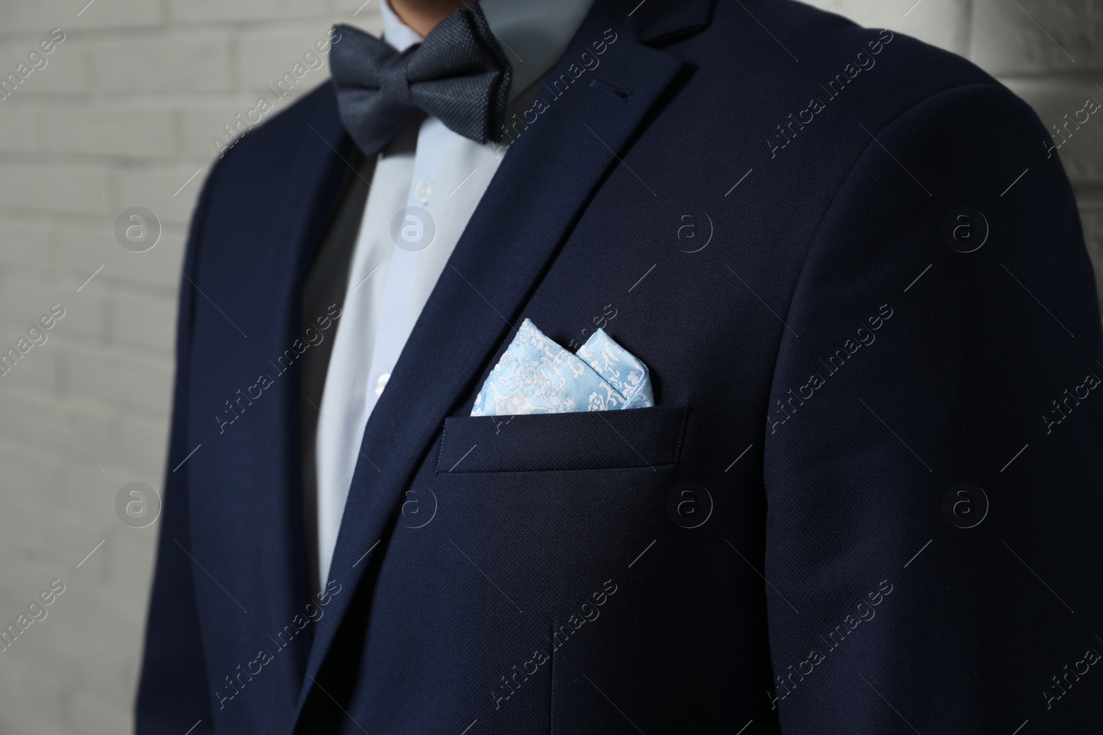 Photo of Man with handkerchief in breast pocket of his suit on light background, closeup