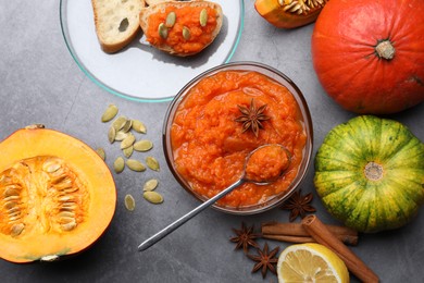Delicious pumpkin jam and ingredients on grey table, flat lay