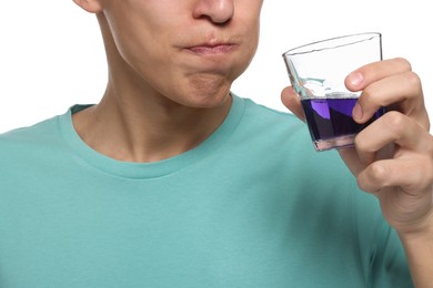 Young man using mouthwash on white background, closeup