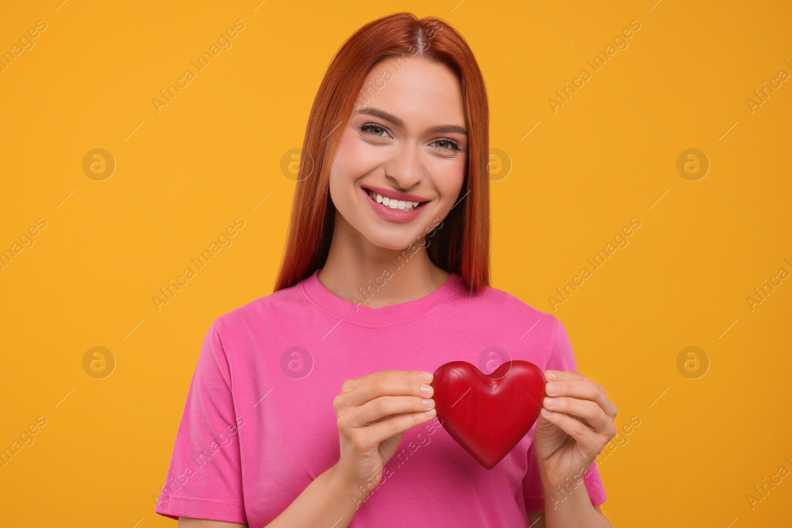 Photo of Beautiful happy woman with red heart on orange background