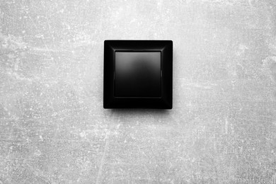 Photo of Black light switch on grey background, top view