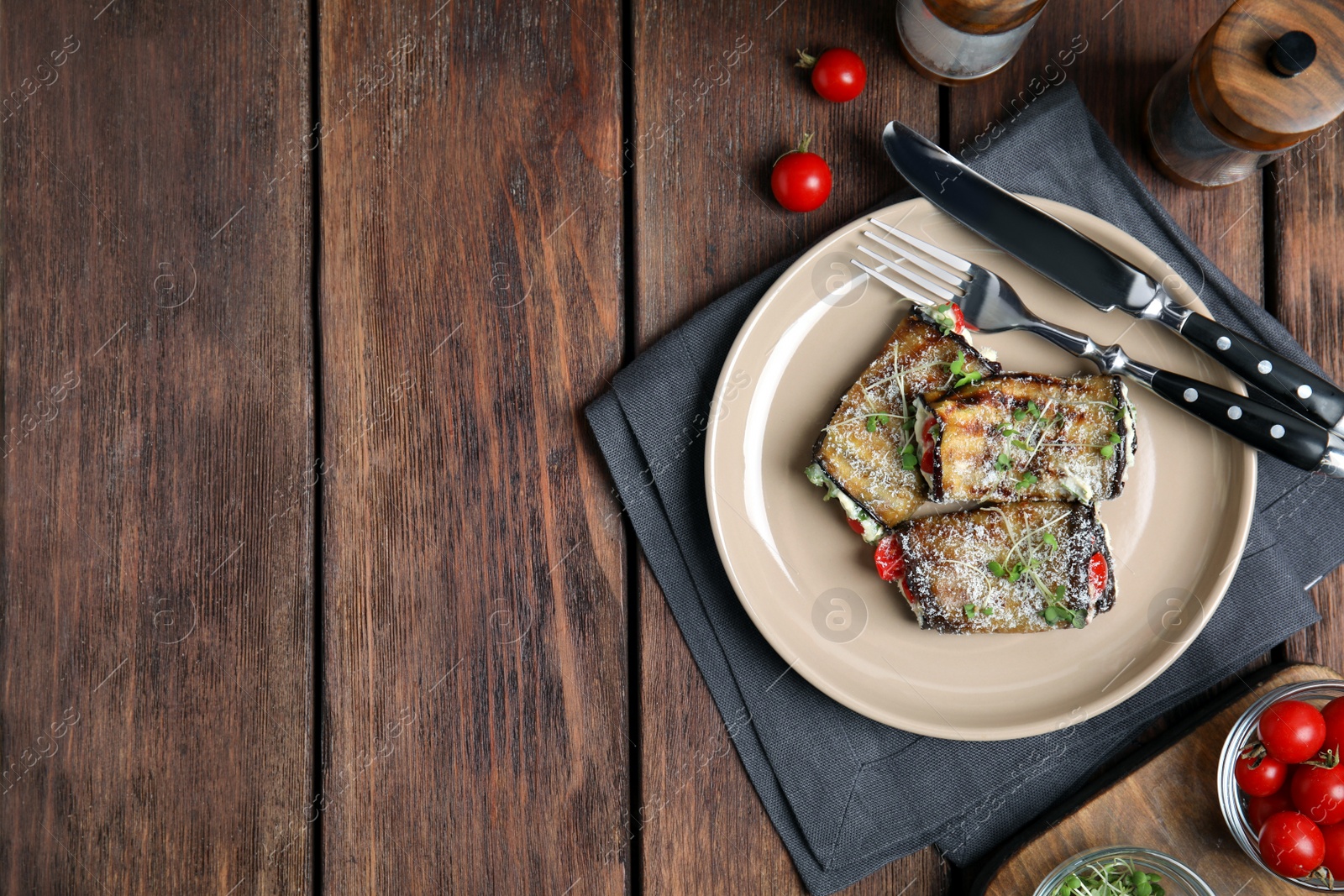 Photo of Delicious baked eggplant rolls served on wooden table, flat lay. Space for text