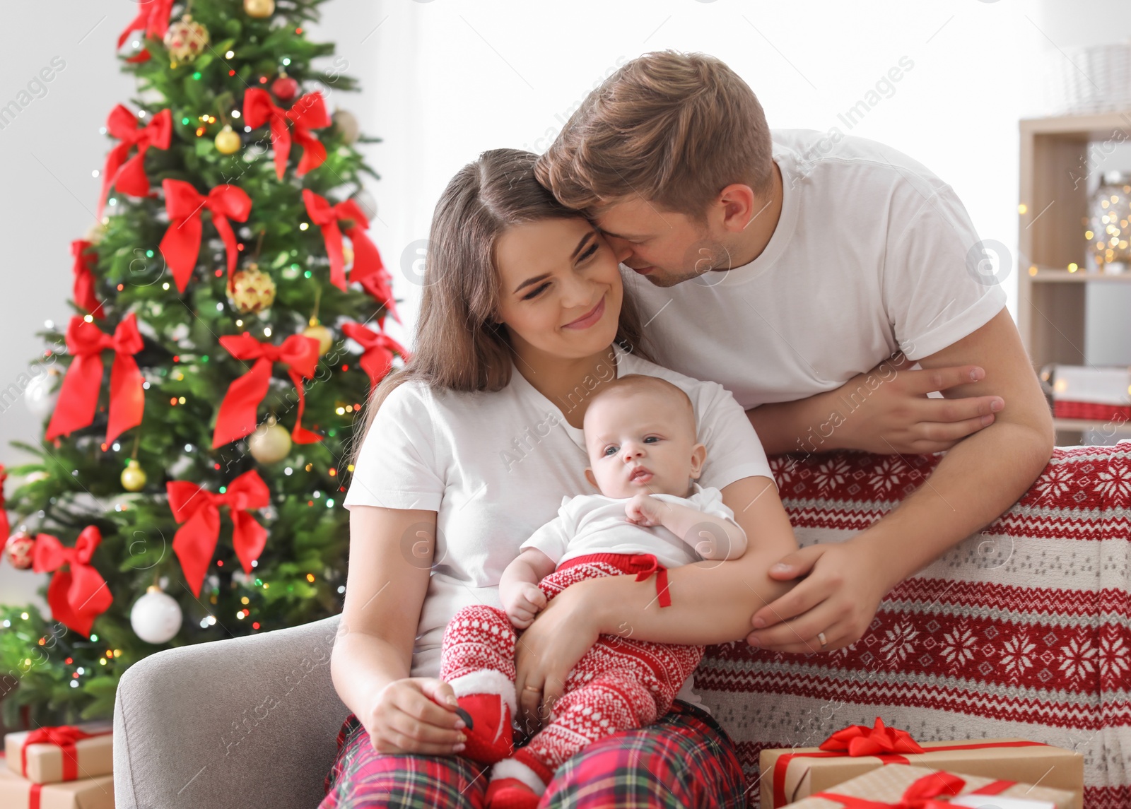 Photo of Happy couple with baby celebrating Christmas together at home