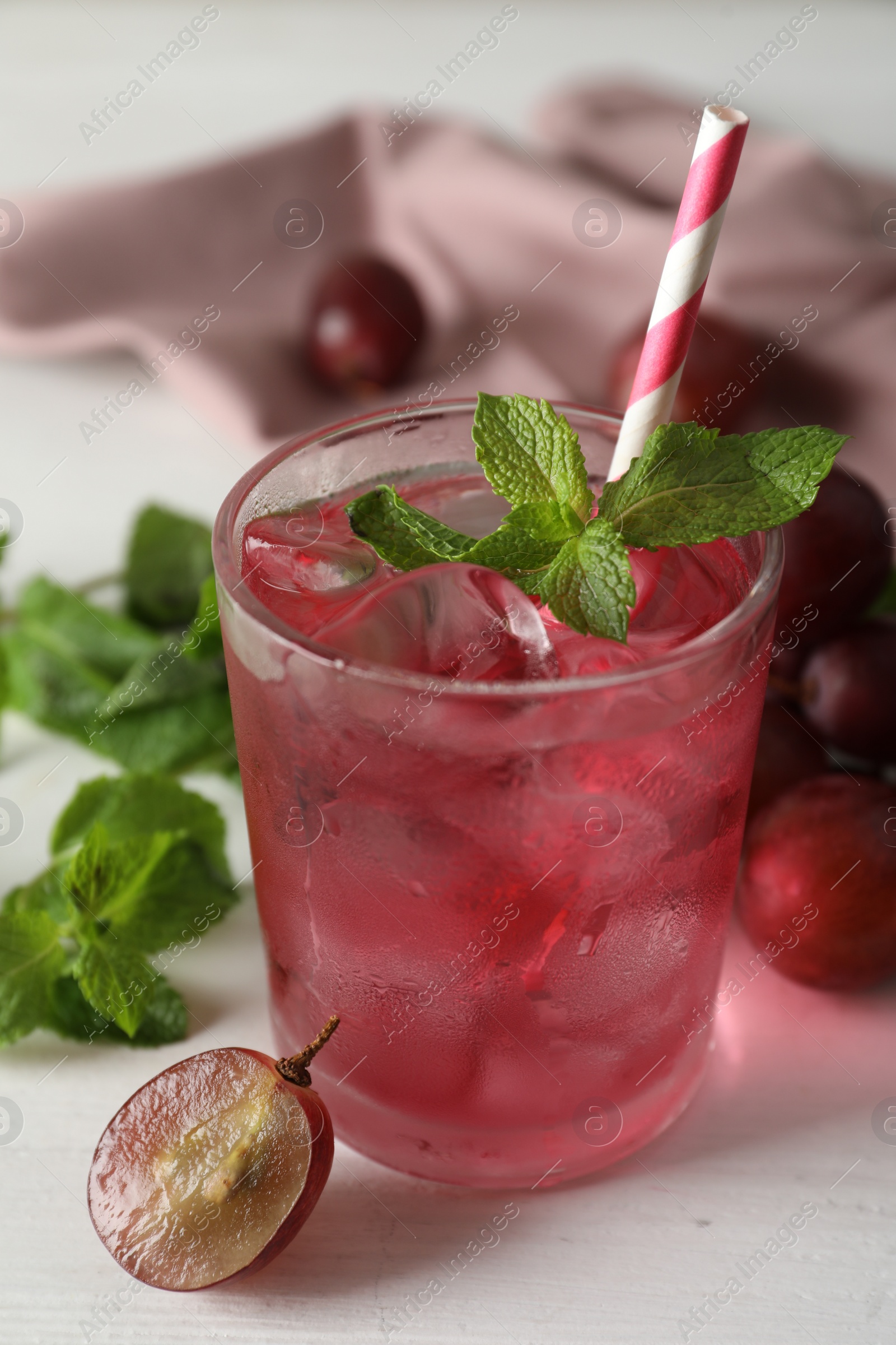 Photo of Delicious grape soda water with mint on white table. Refreshing drink