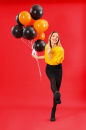 Photo of Beautiful woman with balloons on red background. Halloween party