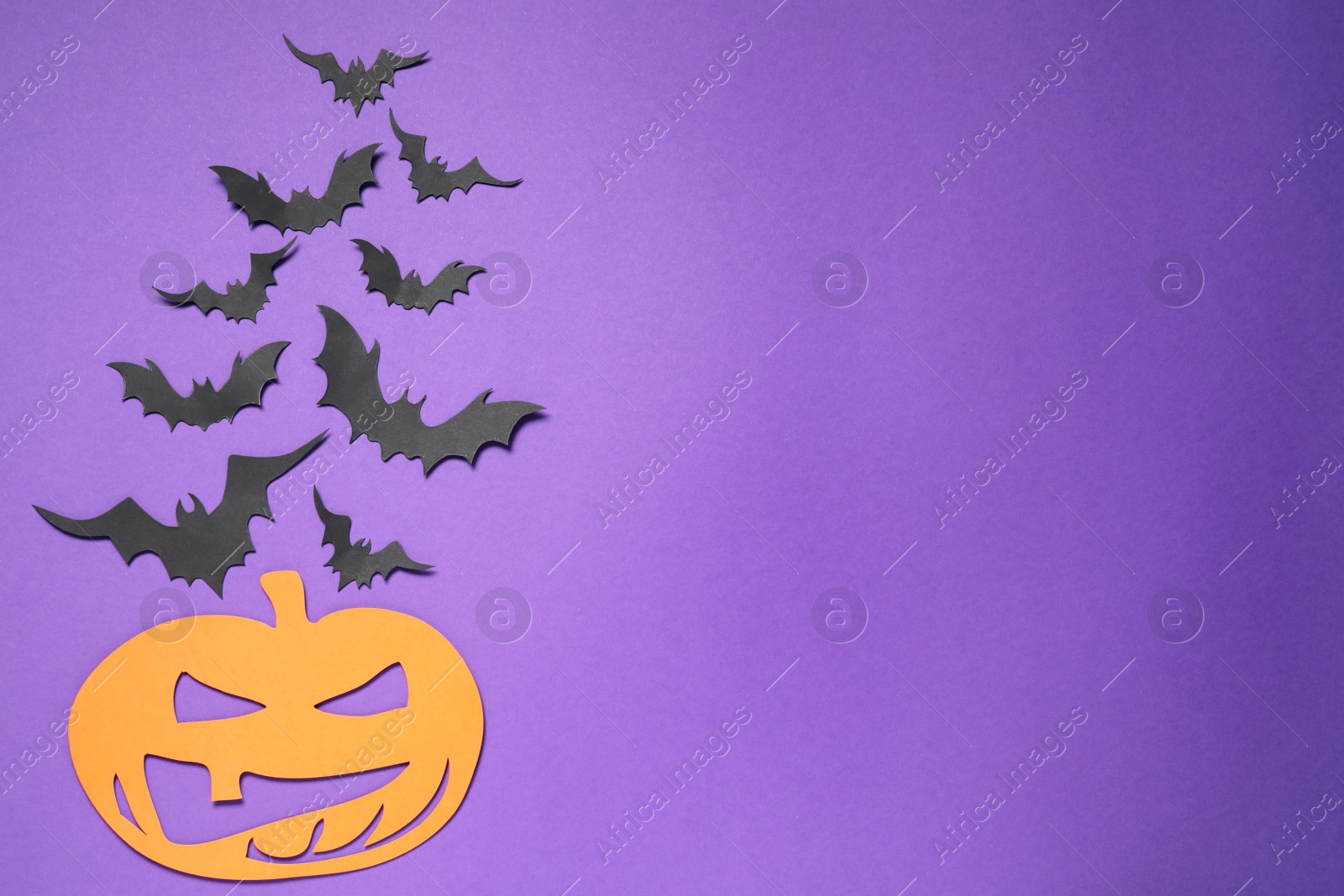 Photo of Flat lay composition with paper bats and pumpkin on purple background, space for text. Halloween decor