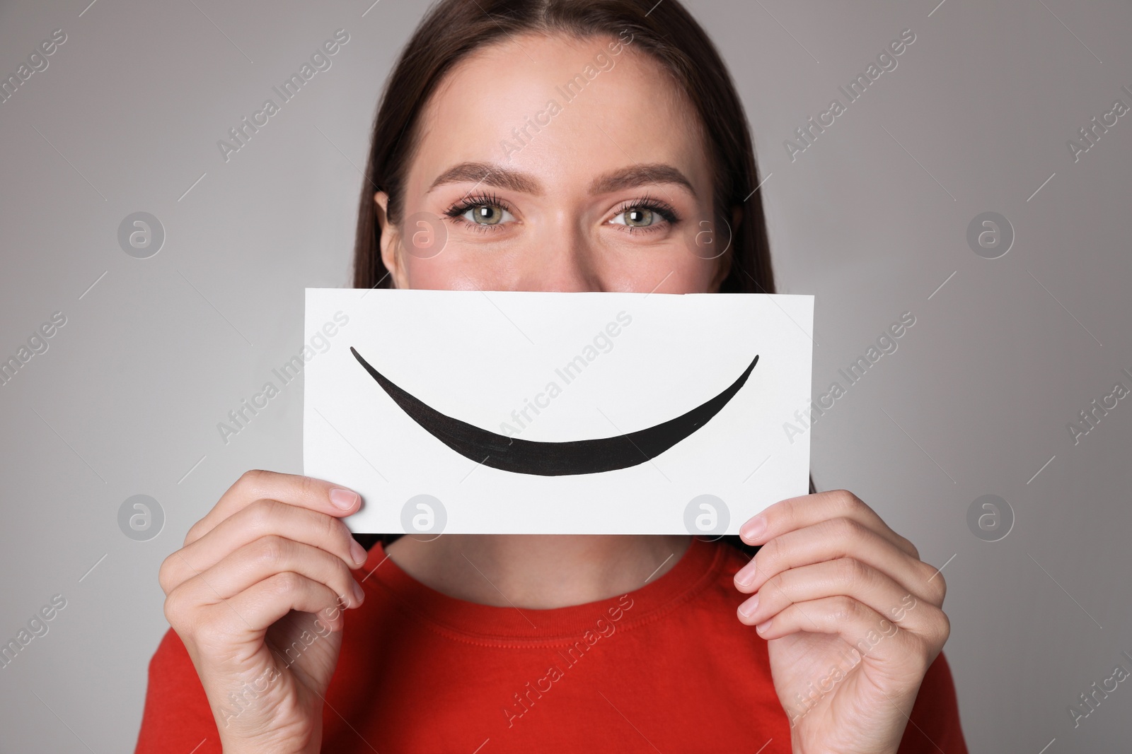 Photo of Woman holding sheet of paper with smile on grey background