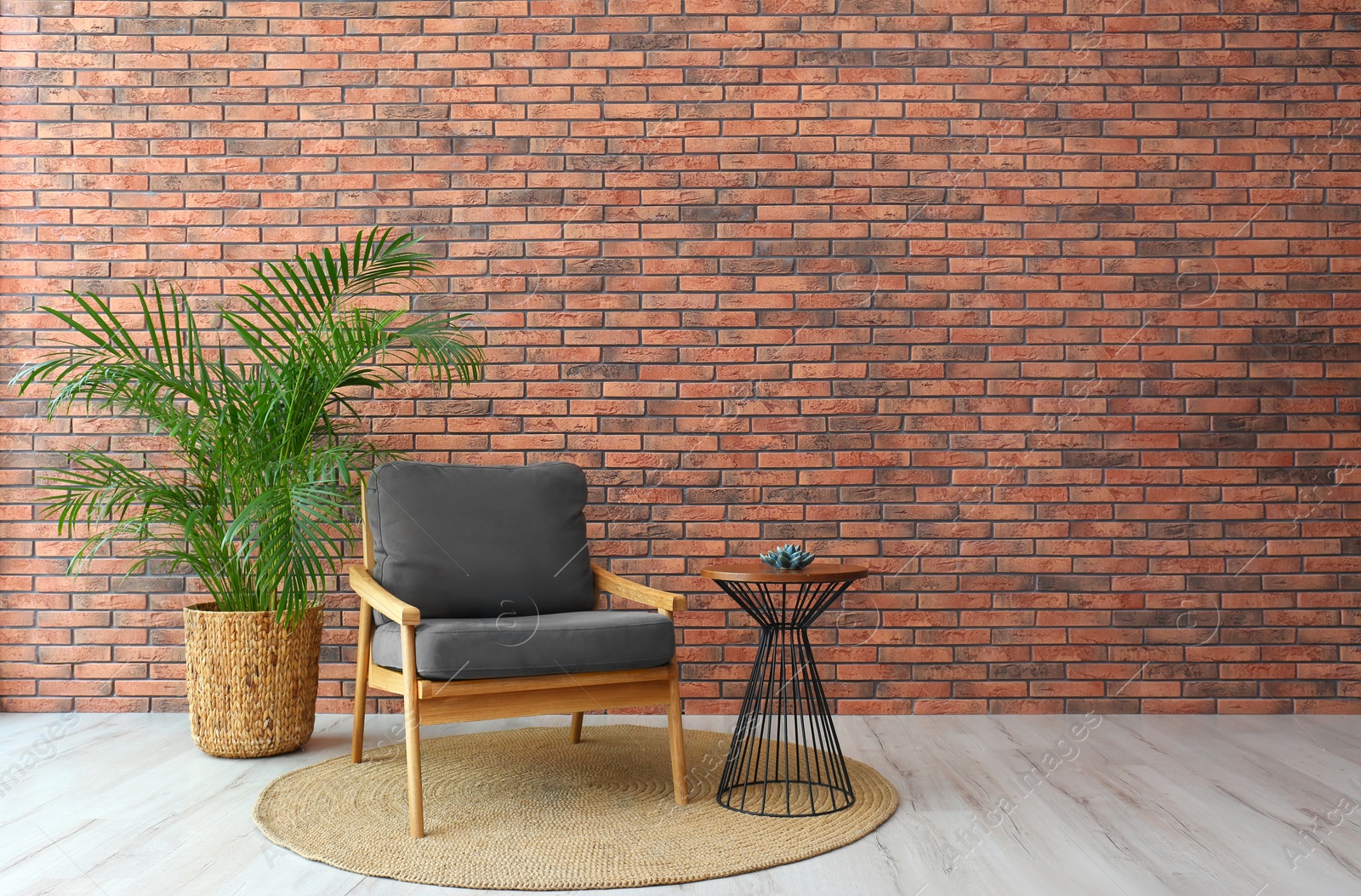 Photo of Modern room interior with stylish grey armchair and potted plant near brick wall