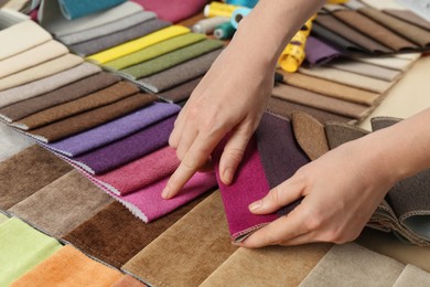 Photo of Woman choosing among colorful fabric samples, closeup