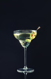 Photo of Martini cocktail with olives on dark background, space for text
