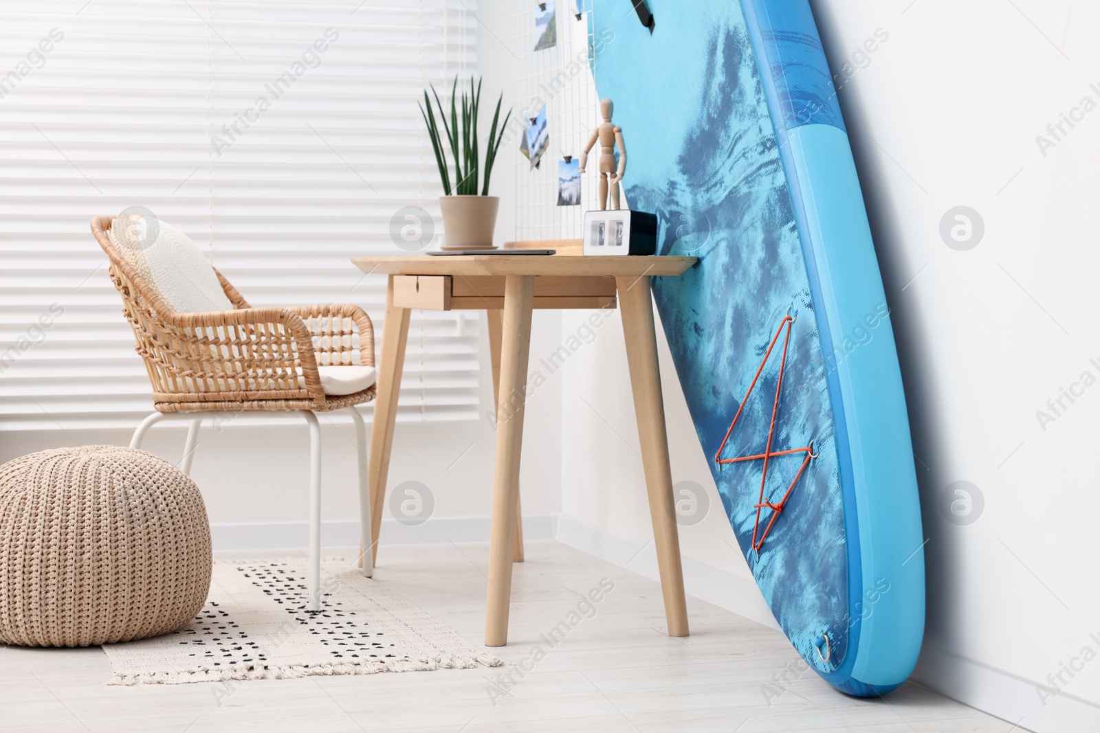 Photo of SUP board and workplace in room. Interior design