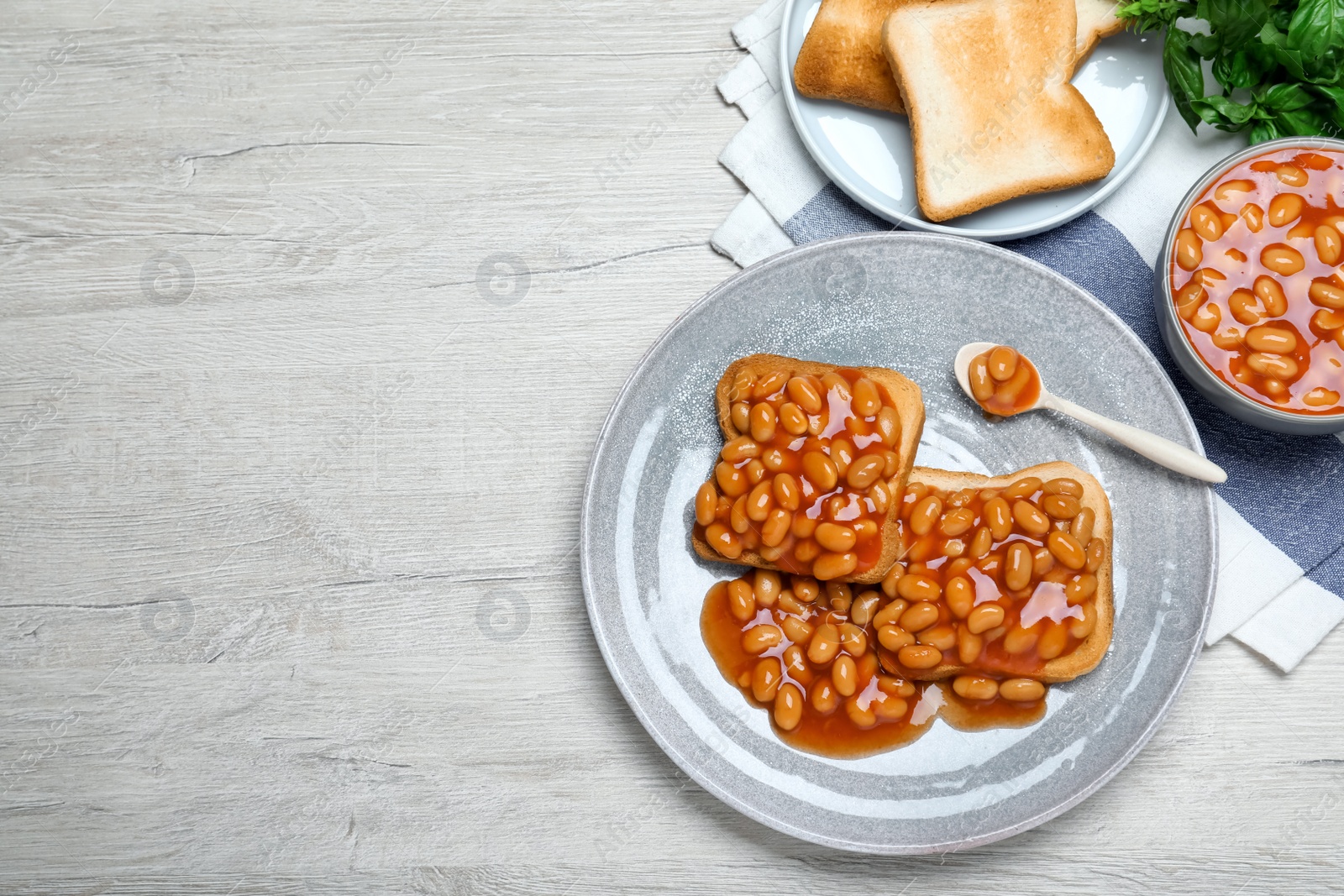 Photo of Toasts with delicious canned beans on white wooden table, flat lay. Space for text