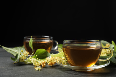 Photo of Tasty tea and linden blossom on black table. Space for text