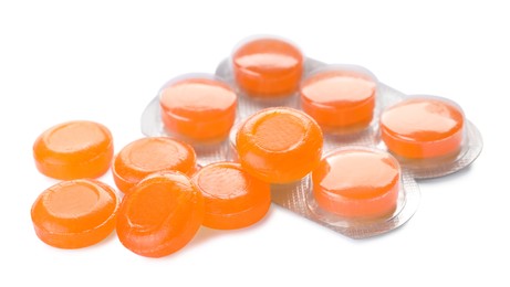 Many orange cough drops on white background