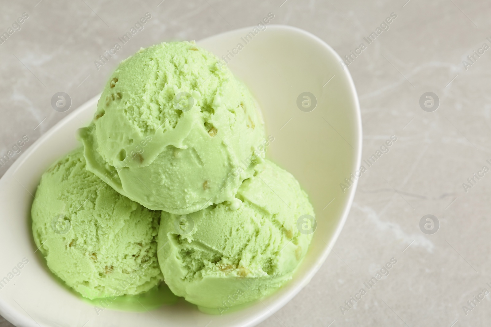 Photo of Tasty pistachio ice cream on light table, closeup view
