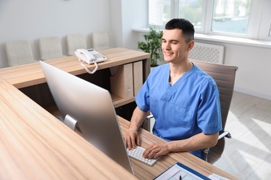 Smiling medical assistant working with computer at hospital reception