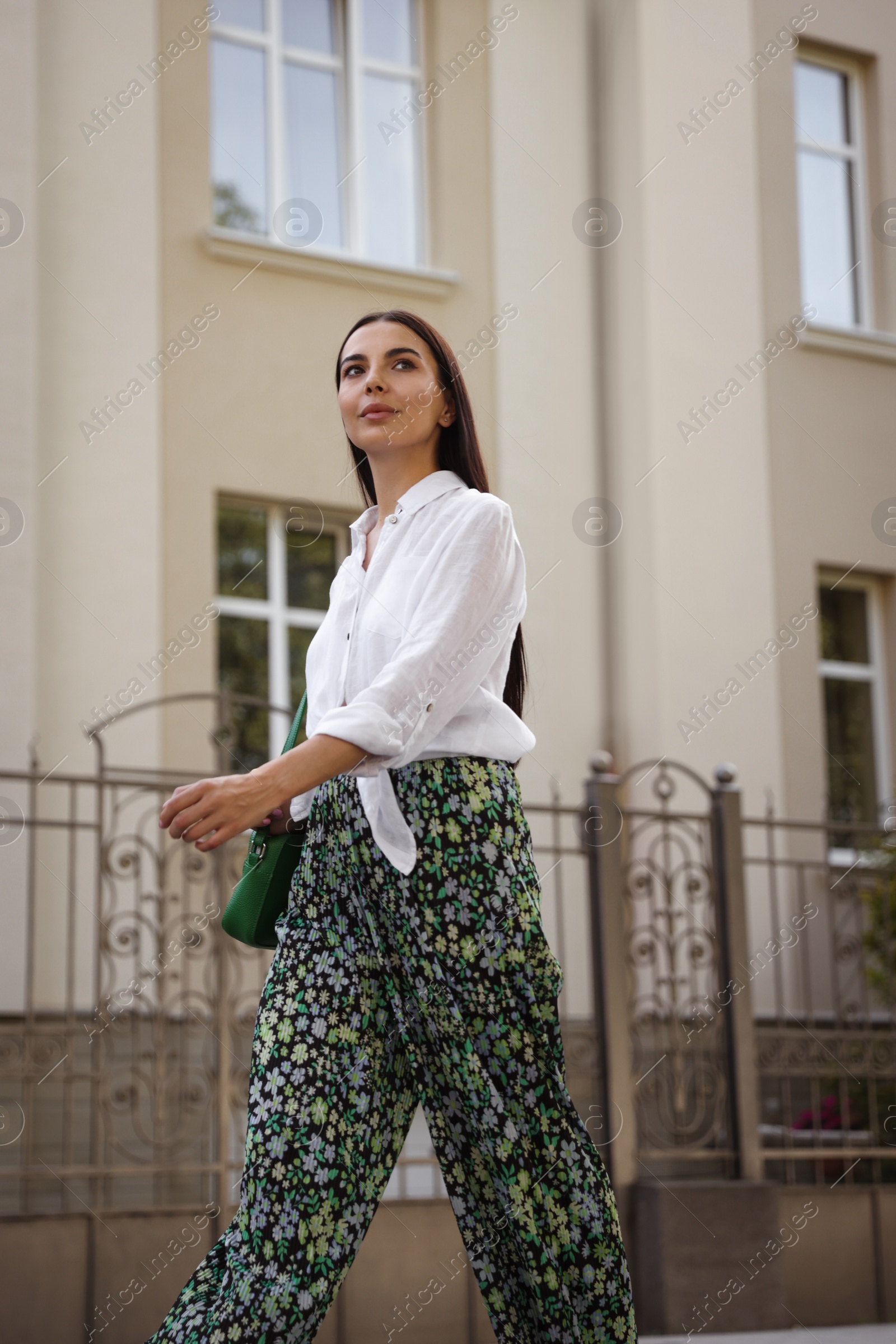 Photo of Beautiful young woman in stylish outfit walking on city street