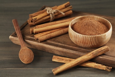 Photo of Aromatic cinnamon sticks and powder on wooden table