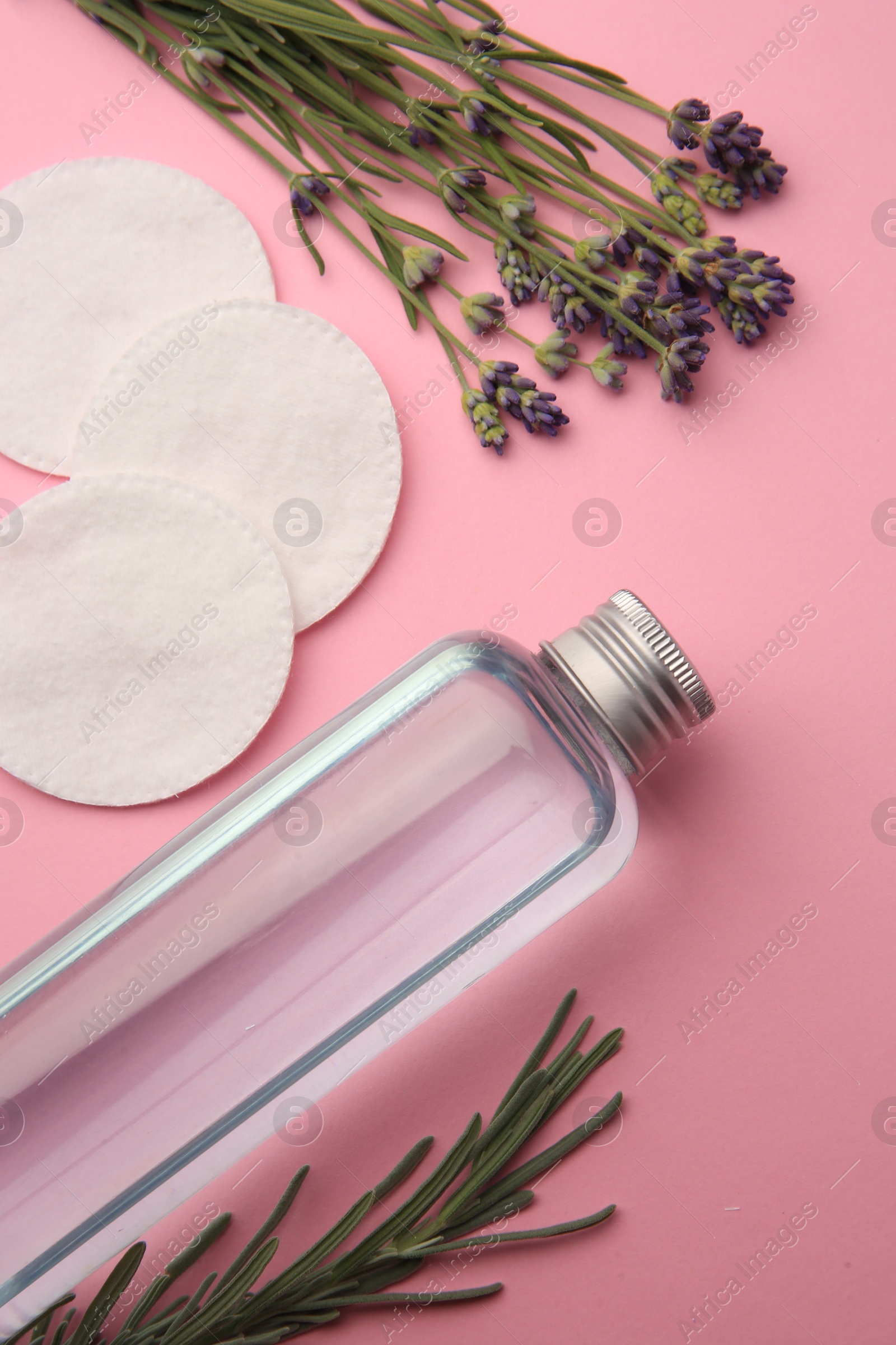 Photo of Flat lay composition with bottle of makeup remover and cotton pads on pink background