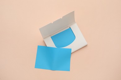 Photo of Package with facial oil blotting tissues on beige background, flat lay. Mattifying wipes