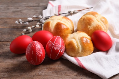 Photo of Red painted Easter eggs and buns on wooden table