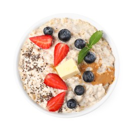 Photo of Tasty boiled oatmeal with berries, chia seeds and peanut butter in bowl isolated on white, top view